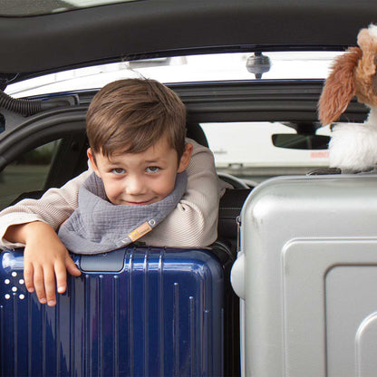 Junge mit Löwenkind Halstuch auf Koffern im Kofferraum eines Autos